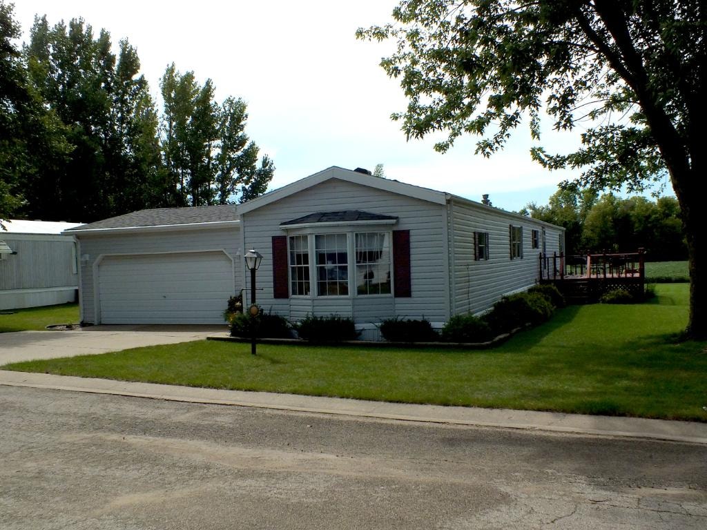 Gray home with attached garage and landscaping at Knollwood Estates